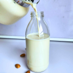 A jar of almond drink pouring inside a glass