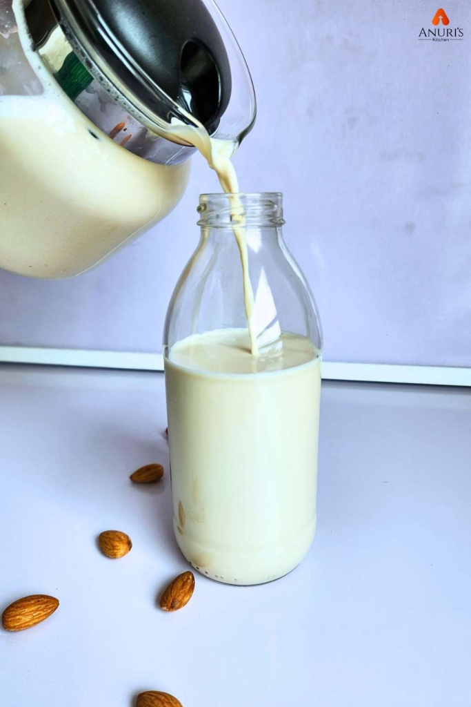 A jar of almond drink pouring inside a glass